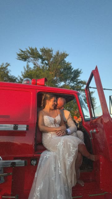 A newly married couple embracing in a bright red truck